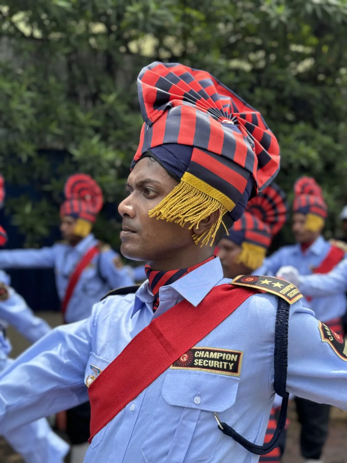 Uniformed officer wearing parade headwear with personnel behind him