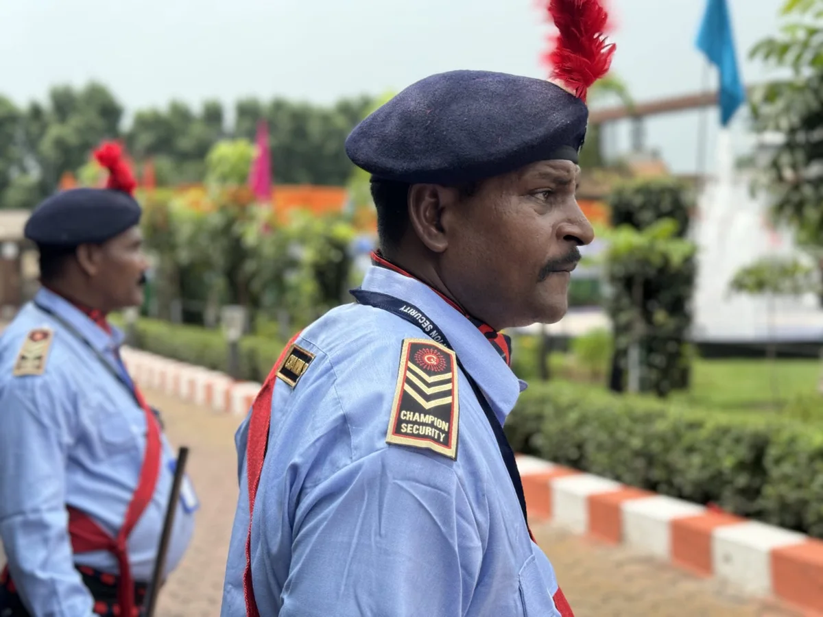 Uniformed security officer outdoors with personnel in the background