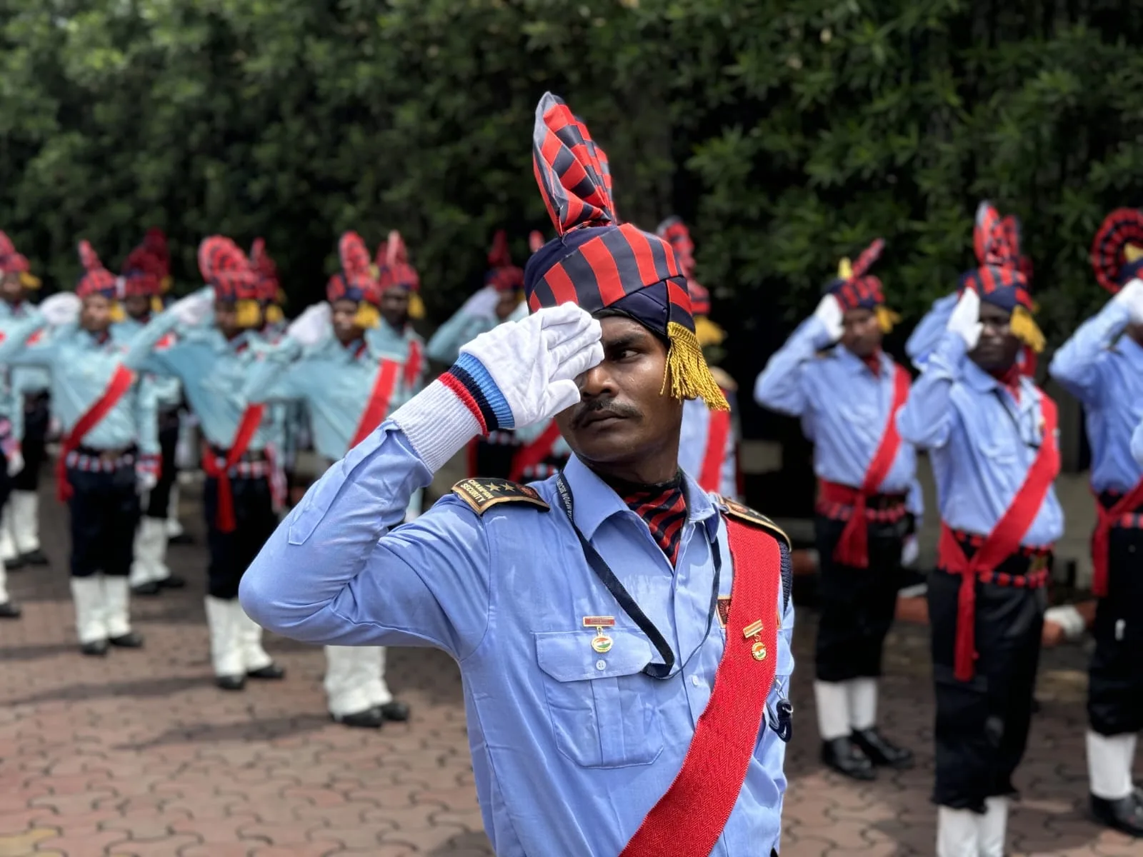 Champion Security officer saluting with a uniformed team in formation